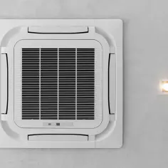 Kasetonowa klimatyzacja na suficie obok kwadratowej lampki.